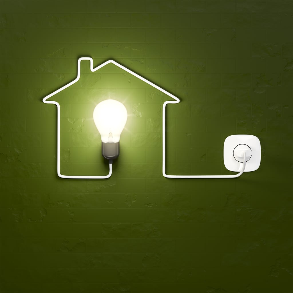 A lit-up lightbulb encircled by a power cord shaped like a house on a green background, signifying whole home electrification.